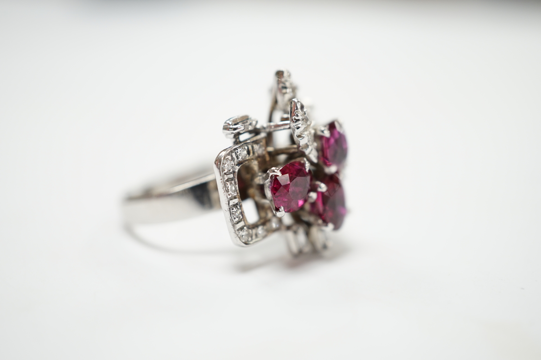 A recent 18k white metal, ruby and diamond cluster set modernist dress ring, size N/O, gross weight 5.7 grams.